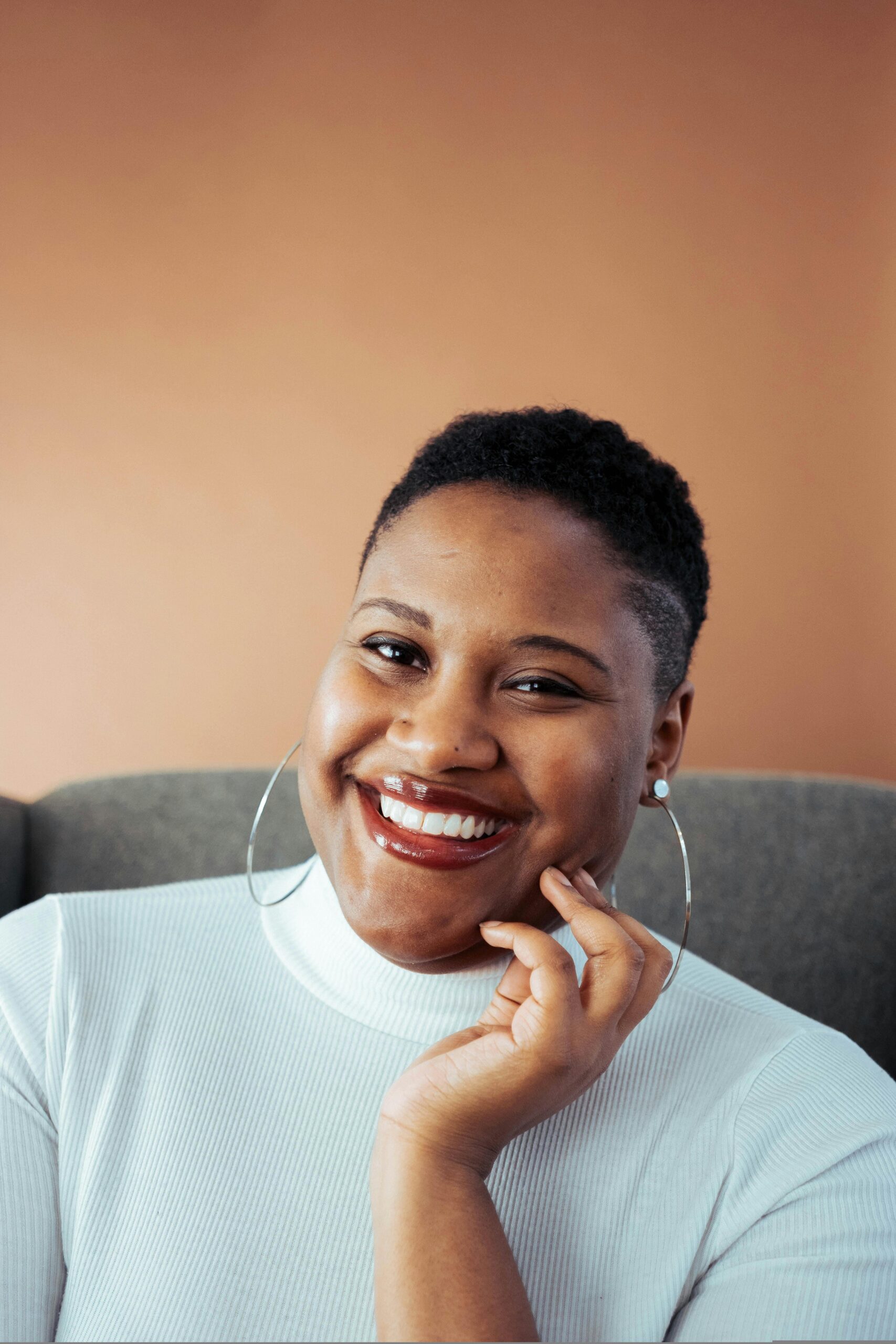 Smiling woman in white turtleneck posing indoors with a joyful expression.